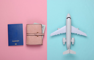Flat lay travel composition on a blue-pink background. Plane figurine, passport, wallet. Rest, vacation and tourism or emigration. Top view.  Minimalism