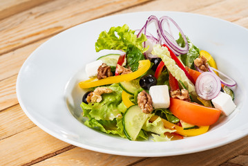 Greek salad with feta cheese on the wooden background