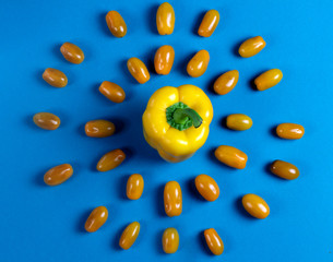Sun made of vegatables: yellow peper and yellow tomates on blue background