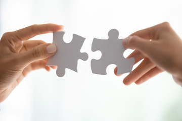 Close up of people assemble jigsaw puzzle find perfect match, business solution, diverse employees...