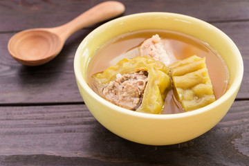 Bitter gourd soup with pork ribs in bowl on wood table.