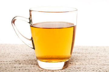 Glass cup of breakfast tea on gentle color background.