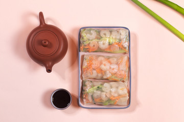 Fresh Spring Roll with shrimps  on a plate, with teapot and souse, Vietnamese Food. Top view, pink background