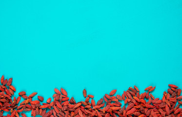 Fototapeta na wymiar Goji berries on aqua background, copy space top view