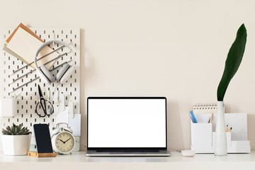 Laptop with blank white screen on office desk interior. Stylish gold workplace mockup table view. 