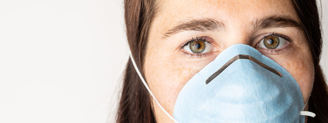 A woman is wearing a face mask for protection from the Corona Virus and has stocked up on her toilet paper stash in case of quarantine.