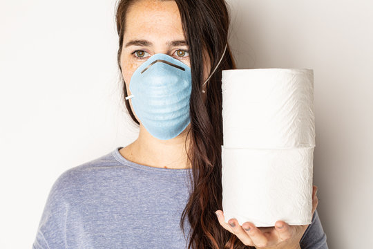A woman is wearing a face mask for protection from the Corona Virus and has stocked up on her toilet paper stash in case of quarantine.