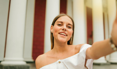 Selfie portrait of a cheerful charismatic woman against the background of a building with columns in the outdoor