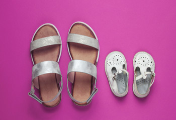 Kids and adults fashionable sandals on pink background. Top view