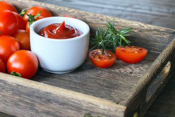 ketchup in a bowl , halves of fresh tomatoes , sprigs of rosemary and whole tomatoes close-up. background with ketchup, tomatoes, rosemary.