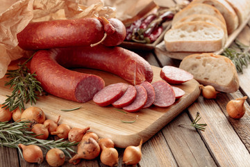 Smoked sausage with bread and spices on a old wooden table.