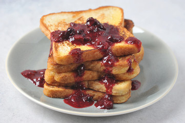 Toast with berry jam on a plate. Light background. Close-up. Macro shot.