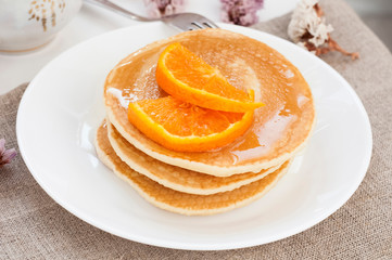 Pancakes stack on a white plate and tablecloth. Tasty breakfast