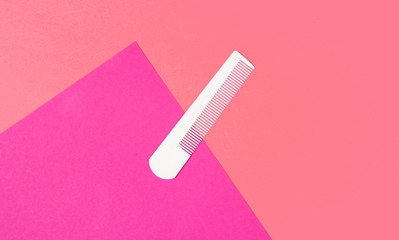 White plastic comb on pink background. Hair care, beauty concept. Top view