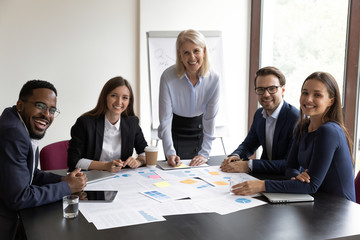 Group portrait of smiling diverse businesspeople gather at desk in boardroom brainstorming working together, happy multiracial colleagues posing cooperating in office meeting, collaboration concept