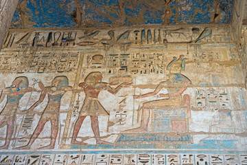 Hieroglyphic painted carvings on an ancient egyptian temple wall