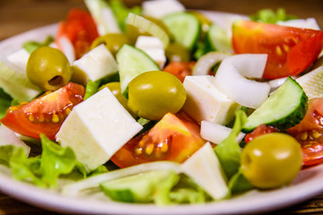 Ceramic plate with greek salad on wooden table