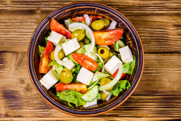 Ceramic plate with greek salad on wooden table. Top view