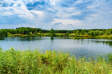 Naklejka na ściany i meble View on a lake in the abandoned sand quarry and dramatic sky