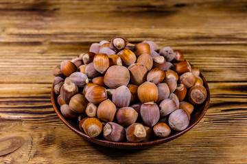 Plate with pile of hazelnuts on a wooden table
