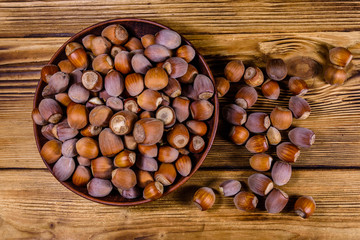 Plate with pile of hazelnuts on a wooden table. Top view