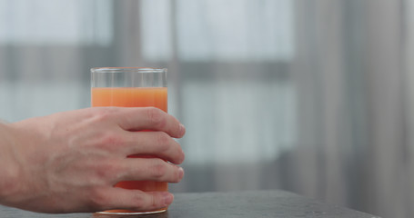 man hand take glas with grapefruit juice from concrete surface