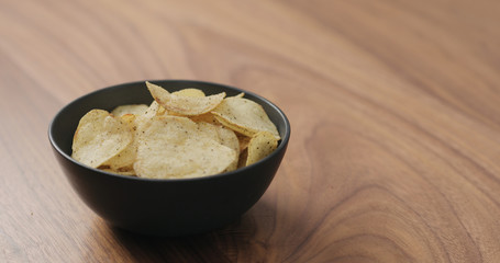 potato chips with black pepper in black bowl on walnut table