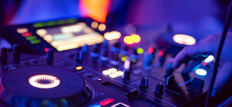 DJ Spinning, Mixing, and Scratching in a Night Club. DJ playing music at mixer . Closeup. Party.