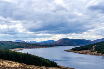 Beautiful layers of color of rural Isle of Skye landscape on an overcast day. From loch shore at low tide to the rolling hills of the countryside and the Cuillin mountain range