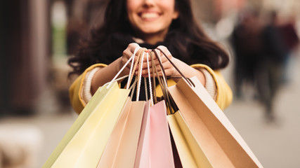 Young woman holding and showing her shopping bags