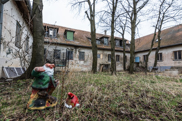 gartenzwerg mit kopf auf dem boden bei verlassenen haus