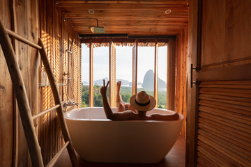 A man is enjoy life by sitting in the bath tub and looking at the beautiful view of Samed Nang She of Phang Nga bay in Phang Nga province, Thailand during summer time.