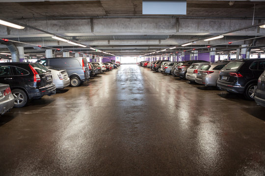 Cars are on a multistorey parking lot, all places are occupied, red lights above vehicles