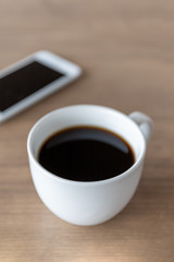 hot coffee cup on wooden table with soft-focus and over light in the background