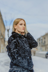 young attractive woman in a fur coat outdoors, portrait of a beautiful girl in winter in the cold...