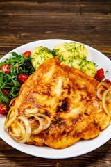 Schnitzel with boiled potatoes on timber background