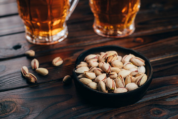 Appetizing salty beer snacks. Two mugs of craft lager and pistachios. Oktoberfest food, pub concept