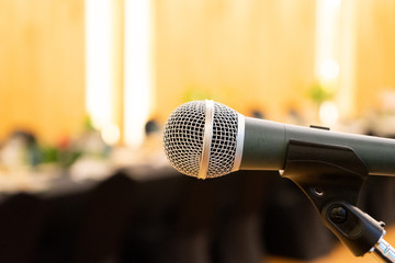 Close up to microphone beside the podium with blur long black table dinner time in tungsten warm light.