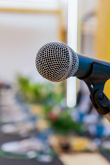Close up to microphone beside the podium with blur long black table dinner time in tungsten warm...