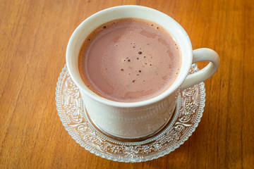 Hot chocolate drink (minuman coklat) in a white cup on wooden background