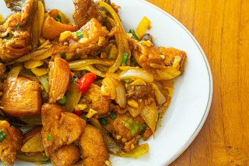 Delicious fried chicken butter in Indonesia called ayam goreng mentega, in white plate on wooden background