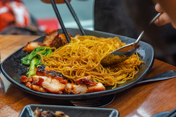 People using chopsticks eating Chinese honey grilled pork noodles 