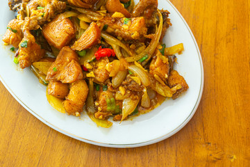 Delicious fried chicken butter in Indonesia called ayam goreng mentega, in white plate on wooden background