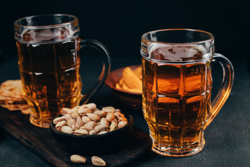 Variety of snacks and mug of light beer. Cheese balls, chips and nuts with two mugs of lager. Bar table. Restaurant, pub, oktoberfest food