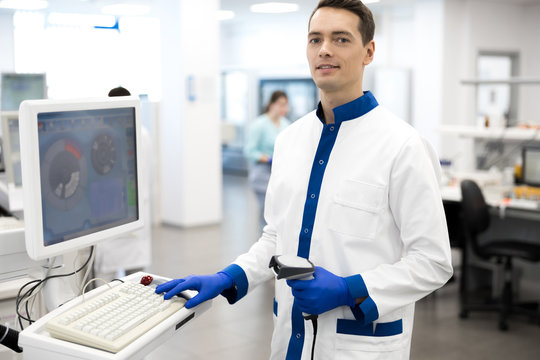 Smiling Male Scientist Using Lab Machine For Pathology Blood Test