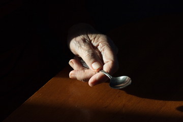 A teaspoon in the hand.  Grandmother's hand holds a spoon. Close-up.