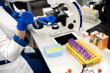 Young female scientist using laboratory sampler during research