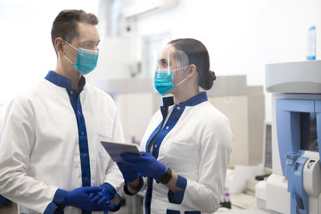 Scientists in medical masks discussing research in laboratory
