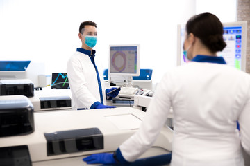 Scientists in protective medical masks working in laboratory