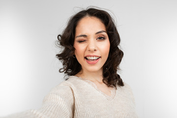 Fototapeta premium young woman model taking selfie while grimacing on gray studio background